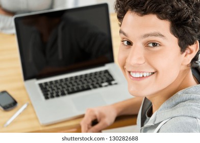 Close-up Of Happy Male Student Working On Laptop