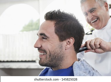 Closeup Of Happy Man Getting An Haircut From Barber In Hair Salon