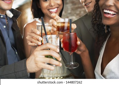 Closeup of happy multiethnic couples toasting drinks at the bar