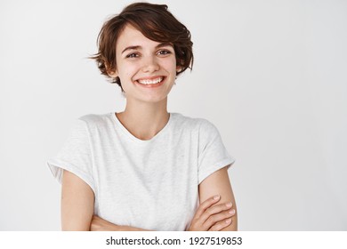 Nahaufnahme eines glücklichen, professionellen Mädchens Querarme auf der Brust, Lächeln auf der Kamera, weißer Hintergrund. Leerzeichen kopieren