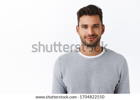 Close-up happy smiling confident macho man with bristle in stylish grey sweater, looking trustworthy and sincere with friendly kind grin, standing white background self-assured and motivated
