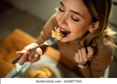 Close-up of happy woman eating pasta for dinner.