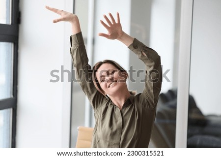 Close-up of happy woman manager raising hands up and celebrating victory in office. Success in business concept