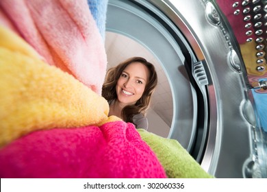 Close-up Of Happy Woman View From Inside The Washer With Clothes