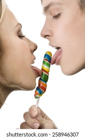 Close-up Of Happy Young Man And Woman Licking A Lollipop At The White Background .