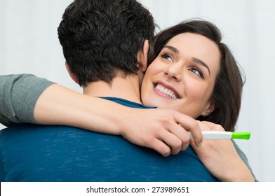 Closeup of happy young woman embracing man after positive pregnancy test