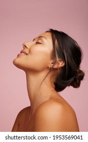 Closeup Of A Happy Young Woman With Healthy Skin. Female Model With Eyes Closed Smiling Over Pink Background.