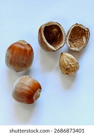 Close-up of hazelnuts in shell and shelled nuts on a white background. The natural texture and warm tones evoke simplicity, nature, and coziness - perfect for healthy eating, organic products, or autu