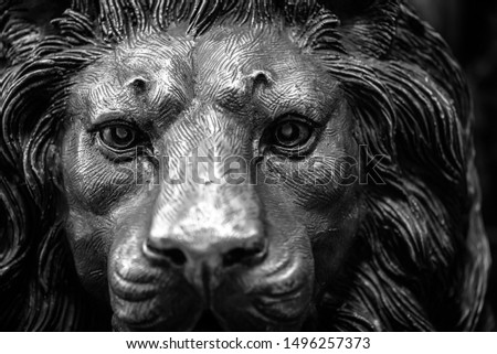 Closeup of a lion’s head carving and sculpture in bronze alloy steel metal with details of eyes and mane in strong material