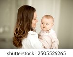 Close-up head shot side view of a mother and her infant daughter. Blurred portraits.