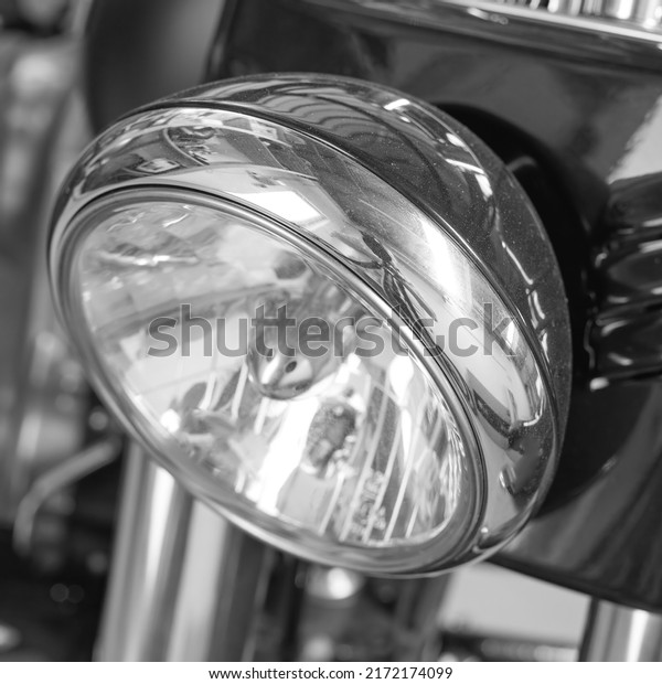Closeup of a headlight on a motorbike. Motorcycle\
light with black and white filter. One light bulb on a sliver\
modern classic chrome coated motor vehicle. Clean, sleek chromium\
maintenance on a bike