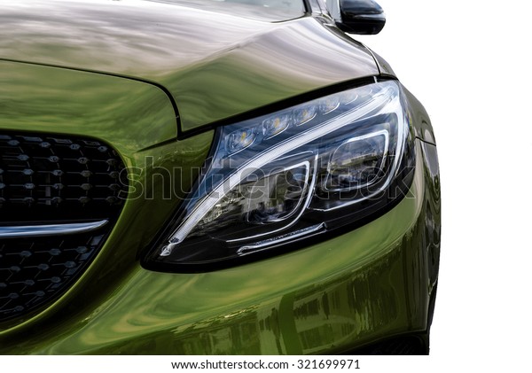 Closeup headlights of  green car and Car exterior\
detail with White background. Closeup headlights of car. Modern\
luxury car close-up banner background. Concept of expensive, sports\
auto Closeup