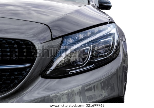 Closeup headlights of grey car and Car\
exterior detail with White back. Closeup headlights of car. Modern\
luxury car close-up banner background. Concept of expensive, sports\
auto Closeup headlights