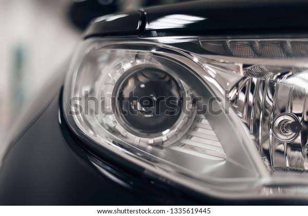Closeup headlights of a modern car. Detail on\
the front light of a car. Modern and expensive car concept. The car\
is in the showroom