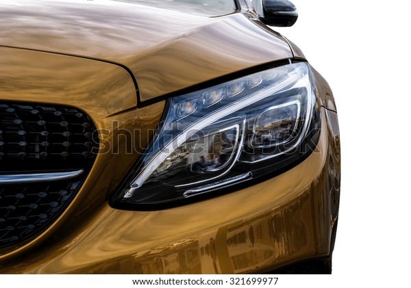Closeup headlights of yellow car and Car\
exterior detail with White back. Closeup headlights of car. Modern\
luxury car close-up banner background. Concept of expensive, sports\
auto Closeup headlights