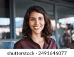 Closeup headshot face portrait of beautiful successful hispanic young business woman looking confident at camera. Smiling latin or eastern middle age female ceo leader businesswoman standing in office