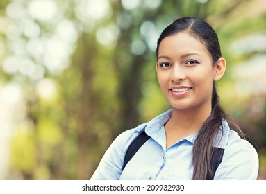 Closeup headshot portrait, happy, young beautiful business woman in blue shirt smiling isolated outdoors background with trees. Positive human emotions, facial expressions