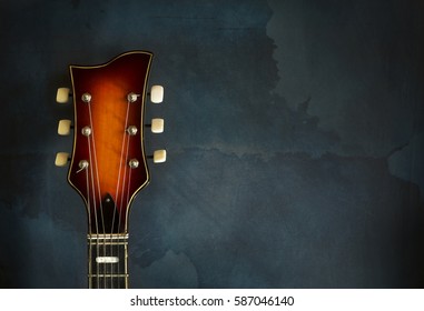 Close-up of headstock old electric jazz guitar on a dark blue background with copy space