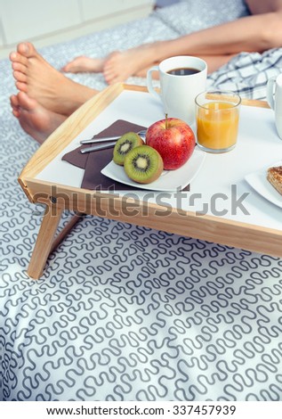 Gesundes Frühstück auf Tablett und Paar Beine im Hintergrund