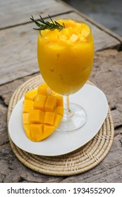 Close-up of Healthy Mango smoothie with fresh mango in a glass placed on a wooden table.