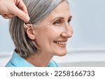 Close-up of hearing aid near senior female patient