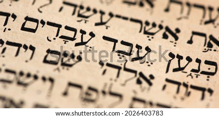 Closeup of hebrew words in Torah page that translate in english as Cursed be Canaan, a servant of servants shall he be to his brothers. Selective focus. Banner