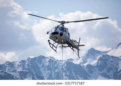 Close-up of a helicopter in the swiss mountains with rope for transport attached - Powered by Shutterstock