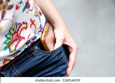 Closeup, High Angle View Of Young Woman Standing On Street, Holding Or , Putting Mobile Phone, Smartphone In Shorts Pocket With One Hand