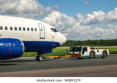 Closeup high detailed view on towing truck pushing back the passenger airplane to the parking place at the airport