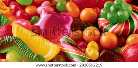 A close-up, high-angle view of a diverse collection of candies, including gummy bears, lollipops, and hard candies, in a variety of bright colors and shapes.