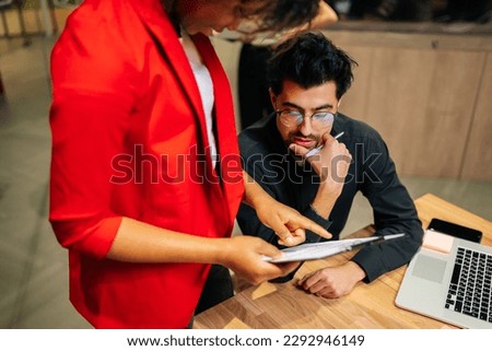 Close-up high-angle view of of serous young businessman reading document at meeting in boardroom. Elegant Caucasian male entrepreneur considering contract. Company ceo analyzing report.