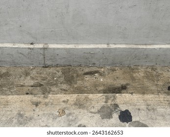 A close-up, high-angle view showcasing the rough and weathered textures of a concrete wall and ground. The image is divided horizontally into sections, revealing different shades and finishes of grey 