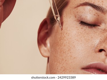 Close-up highly detailed shot of female skin with freckles and pipette with serum. Cropped shot of young woman with smooth perfect skin applying liquid serum on face. - Powered by Shutterstock