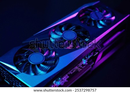 Close-up of high-performance graphics card with three cooling fans with neon lighting. Modern video card for gaming and advanced computing