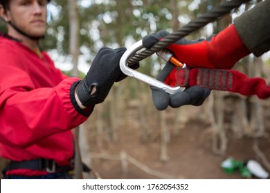 Close-up of hiker adjusting his harness on zip line cable in the forest  - Powered by Shutterstock