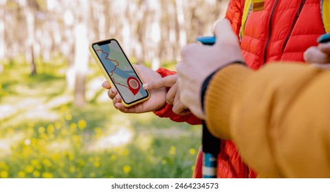 Close-up of hikers using a GPS navigation app on a smartphone to find their route in the forest. - Powered by Shutterstock