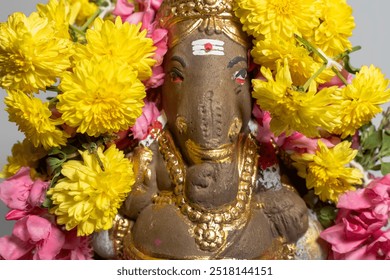 Close-up of Hindu god Ganesha statue made of clay decorated with flower garlands. - Powered by Shutterstock