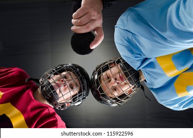 Closeup of a hockey faceoff with teenage hockey players and puck