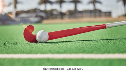 Closeup, hockey and hockey stick with ball on field in sunshine for sport, contest or competition in summer. Sports, turf pitch and artificial grass on ground for exercise, workout and training game - Powered by Shutterstock