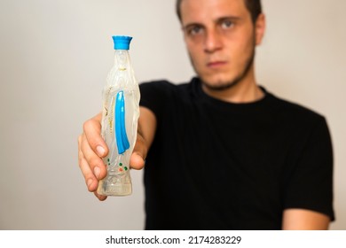 Closeup of the holy water of Lourdes inside a Madonna. It's held by a boy on a white background. Caucasian white man with short hair, little beard and dark eyes.