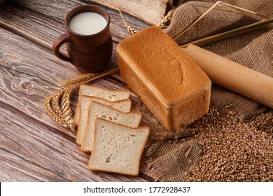 Close-up of homemade bread. Peasant square bread and wheat spikelets with space for text. Homemade baking. White bread with flour and milk on wooden chopping board wheat rye ears copy space. - Powered by Shutterstock