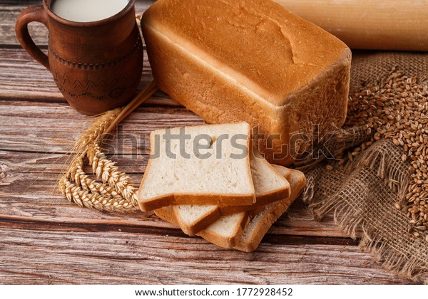 Close-up\
of homemade bread. Peasant square bread and wheat spikelets with\
space for text. Homemade baking. White bread with flour and milk on\
wooden chopping board wheat rye ears copy\
space.