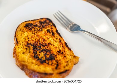 Closeup Of Homemade Cooked Challah Brioche Bread French Toast Fried Serving On White Plate With Fork And Burnt Food