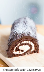 Close-up of homemade delicious rolled cake with chocolate and cream being powdered with vanilla sugar - Shutterstock ID 152968928