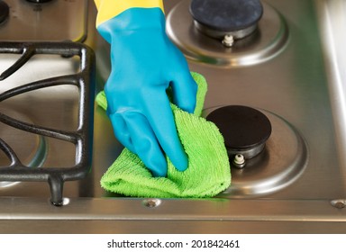 Closeup Horizontal Image Of Hand Wearing Rubber Glove While Cleaning Stove Top Range With Microfiber Rag