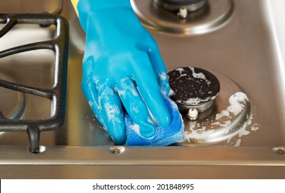 Closeup Horizontal Image Of Hand Wearing Rubber Glove While Cleaning Stove Top Range With Soapy Sponge 