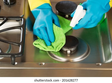 Closeup Horizontal Image Of Hands Wearing Rubber Gloves While Cleaning Stove Top Range With Spray Bottle And Microfiber Rag