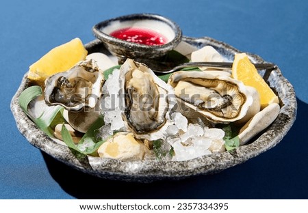  Closeup horizontal view of fresh oysters with lemon on ice, an upscale restaurant dish presentation.