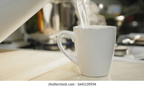 Close-up of hot boiled water is poured into a white ceramic cup on the table in the kitchen, brewing morning coffee - Powered by Shutterstock