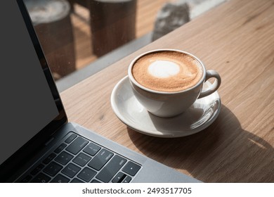 Close-up of Hot coffee latte with latte art milk foam in cup mug and laptop computer on wood desk office desk in coffee shop at the cafe,during business work concept - Powered by Shutterstock